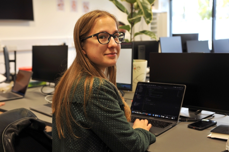 A woman working at her laptop, turned to smile at the camera.