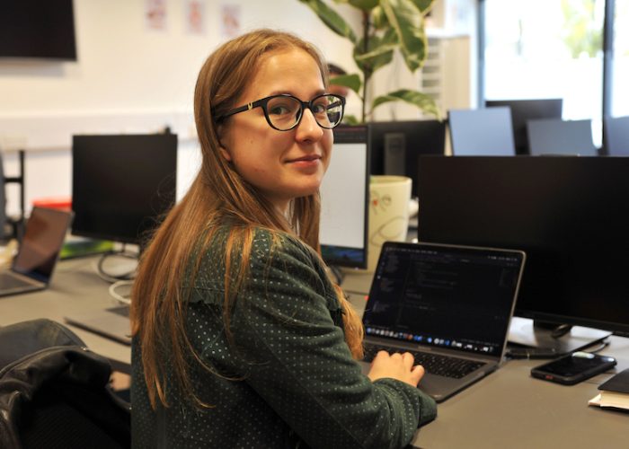 A woman working at her laptop, turned to smile at the camera.